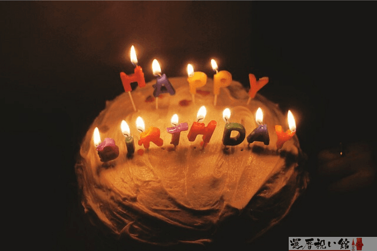 ケーキの上にHAPPY BIRTHDAYという文字のろうそくに火がともっている