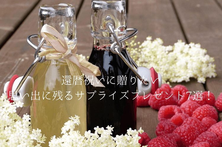 二つの瓶に入ったジュースとその周りにあるクランベリーの実と白いお花