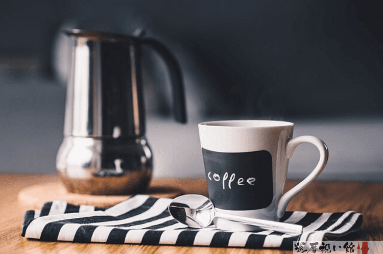 コーヒードリップケトルとコーヒーと書かれたマグカップ、その脇にスプーンが置いてある