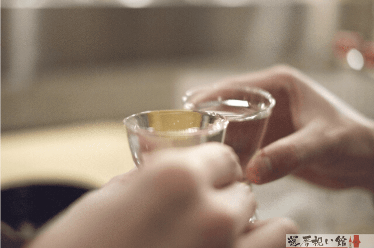ガラス製のおちょこで乾杯する様子
