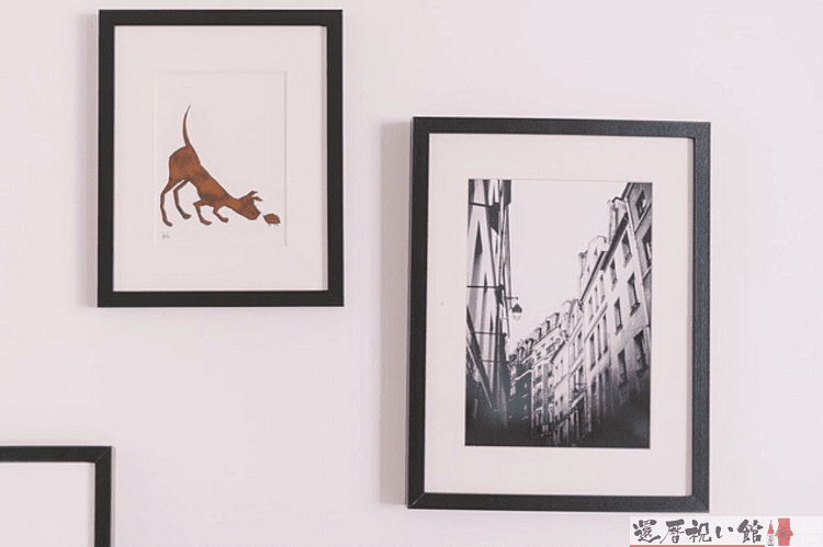 1枚は犬、もう1枚は街並みを描いた絵がフォトフレームに入れて壁に飾られている