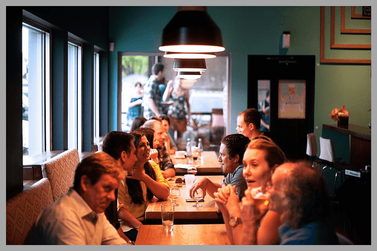 たくさんの人がテーブルに着席して話している海外の飲食店もしくはカフェ