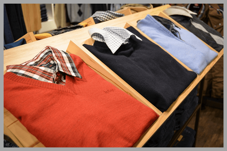 メンズファッションショップ内で赤・黒・水色などのセーターが売られている様子