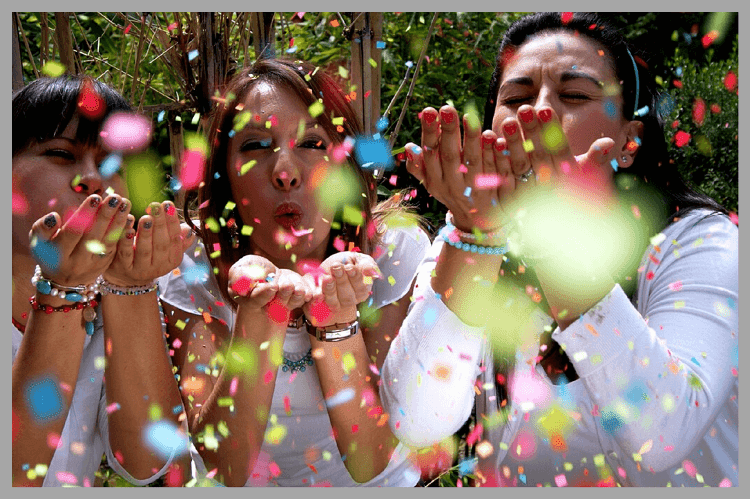 カラフルな紙吹雪を飛ばしてお祝いする3人の外国人の女性