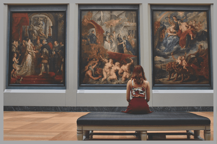 ヨーロッパの歴史ある絵画を美術館で座って眺めている一人の女性