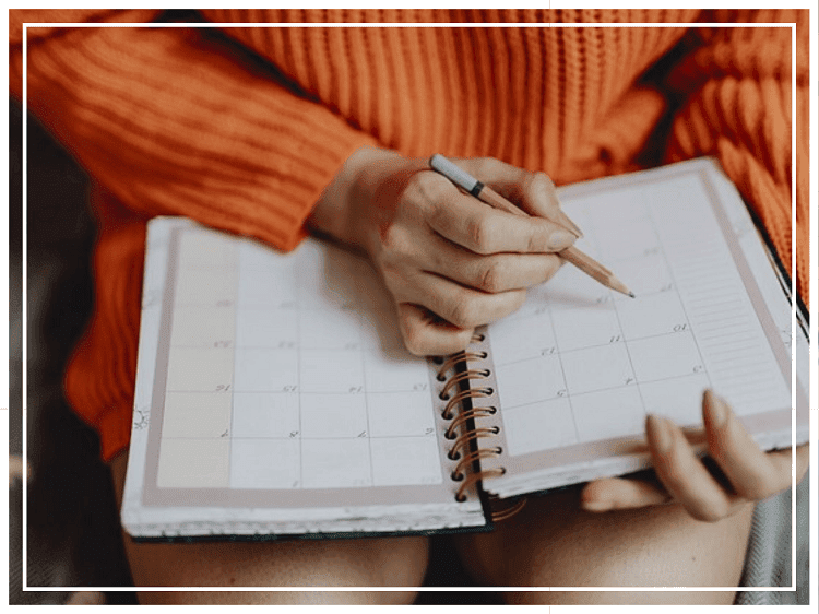 手帳に予定を書き込もうとしている女性