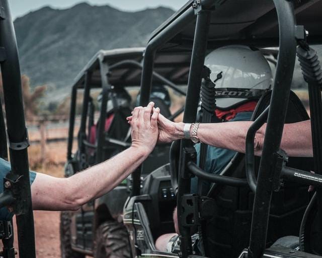 喜寿のカップルが車に乗ってハイタッチ