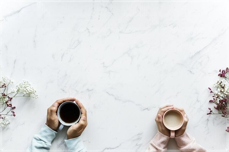 飲み物が入ったマグカップを両手で握っている男女