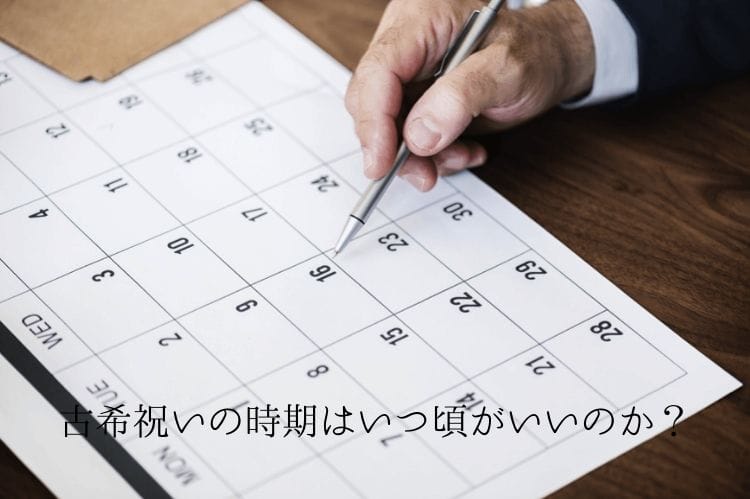 カレンダーをボールペンで指している男性の手