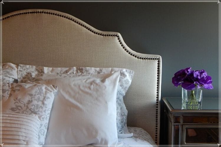 高級なベッドとそのサイドテーブルの上に置かれた紫の花