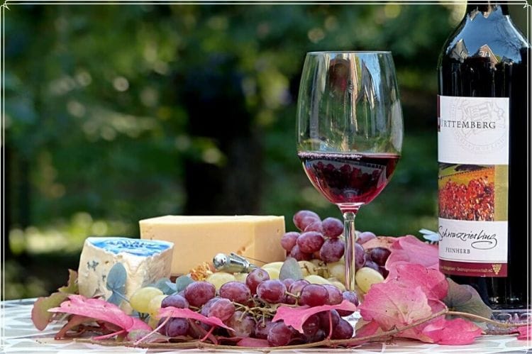 ワインの瓶とそのワインが入ったグラスとチーズ＆ぶどう