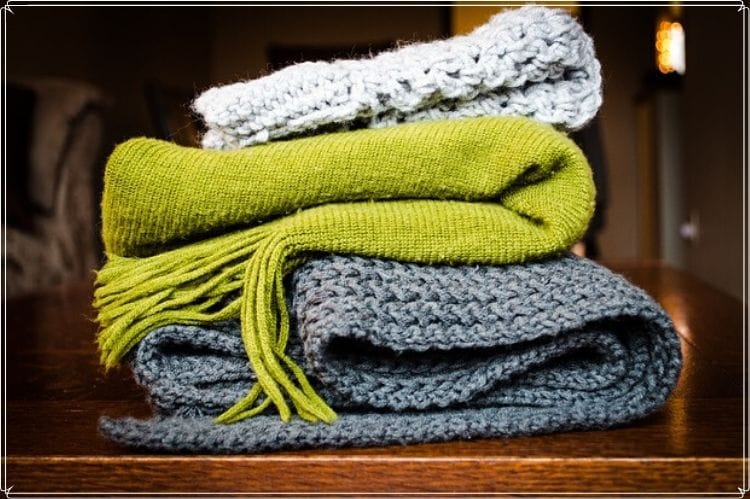 折りたたんで重ねられている灰色や黄緑のマフラー