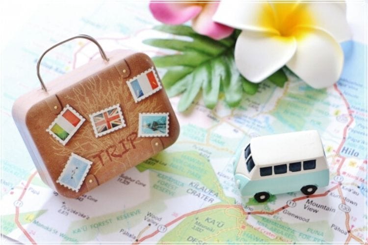 ミニチュアの旅行鞄と車が地図の上に置かれている