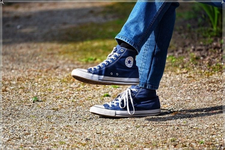青いコンバースのスニーカーを履いた女性の足もと