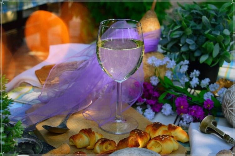 花やパンが置かれたテーブルに白ワインが入ったグラスが置かれている