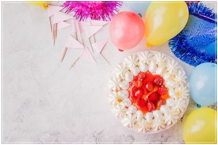 いちごが乗ったフルーツケーキとピンクや黄色の風船とパーティー用の部屋飾りアイテム