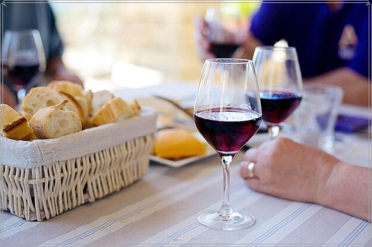 海外のシニアが庭でパンとワインで食事をしている様子