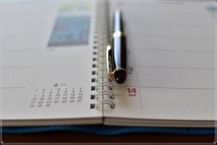 カレンダーの上に置かれた黒いボールペン