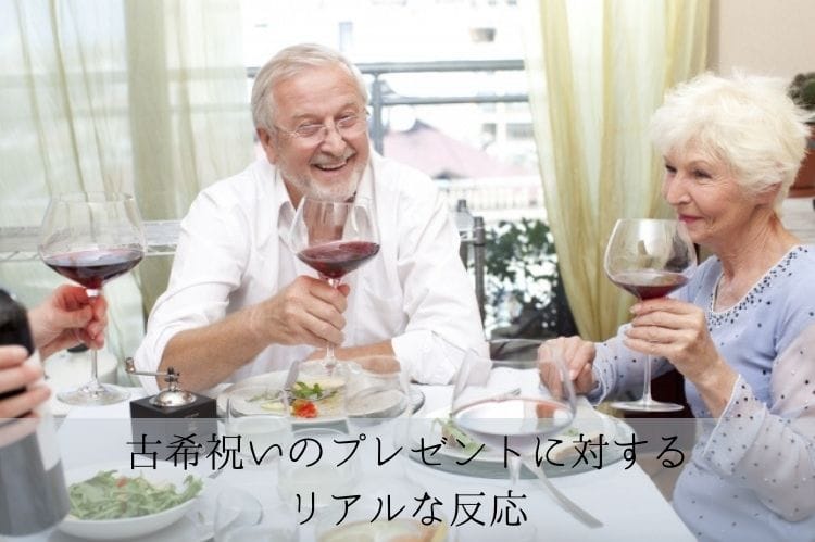 外国のシニア夫婦がテーブルに着席し、ワイングラスをもって笑顔で話をしている様子