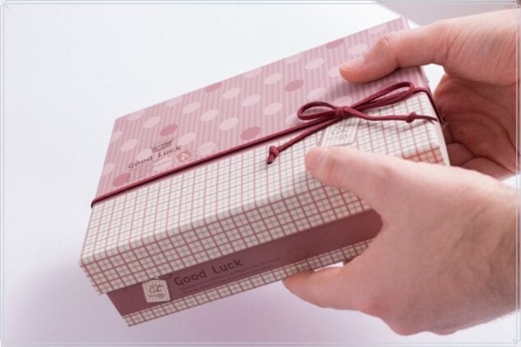 水玉チェック柄半々の包みと赤い紐で結ばれたプレゼントボックスを渡している様子