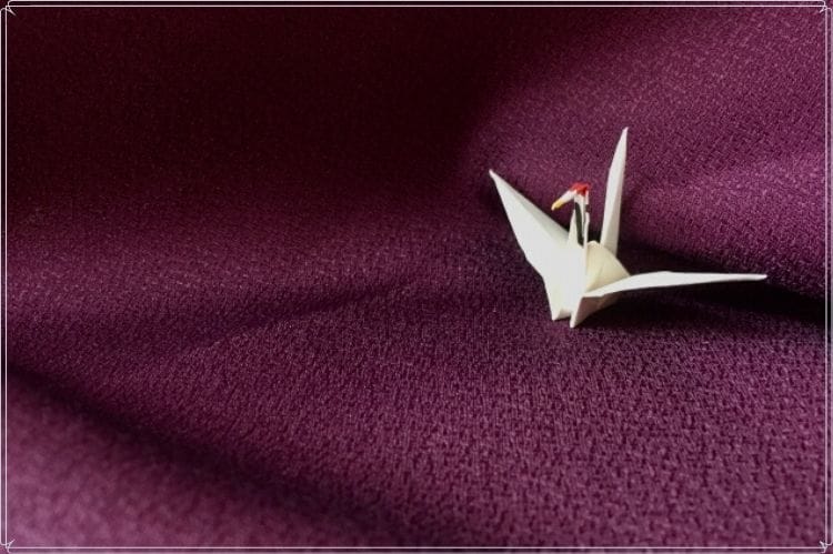 紫色の布の上に白い折り鶴が置かれている