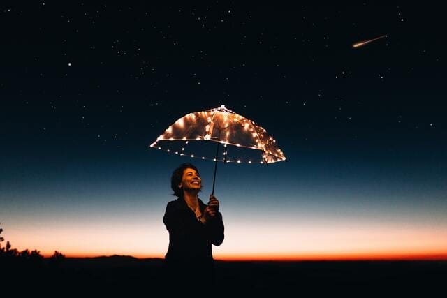 傘寿の女性が星空の下で傘をさしている姿