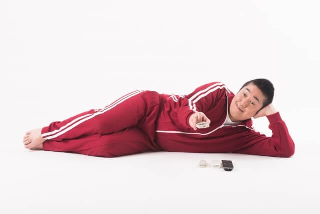 横になってテレビを見る男性