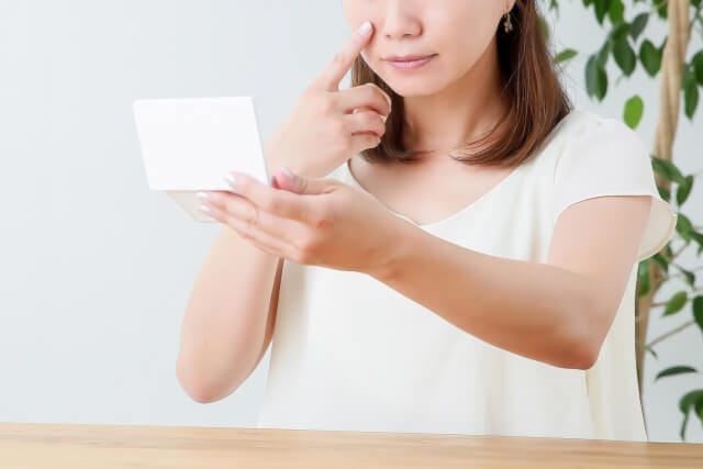 鏡で肌をチェックする女性