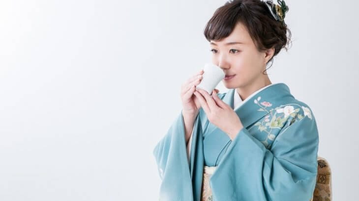 着物を着た女性が日本酒を飲む様子