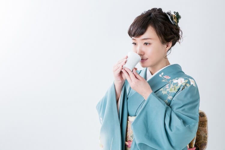 A woman wearing a kimono drinking sake