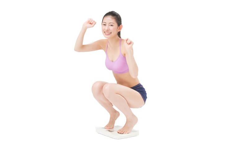 体重計に乗り喜ぶ女性