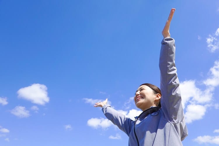 空へ向けて両手を広げる女性