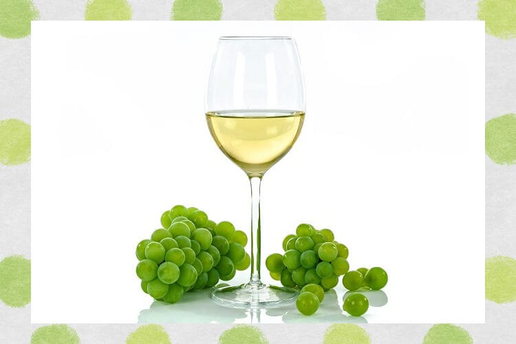グラスに入った白ワインとぶどう