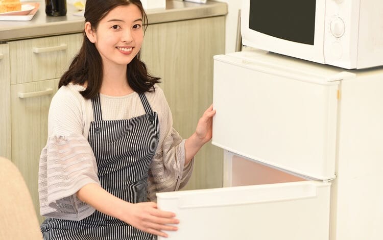 Kvinna som öppnar ett kylskåp