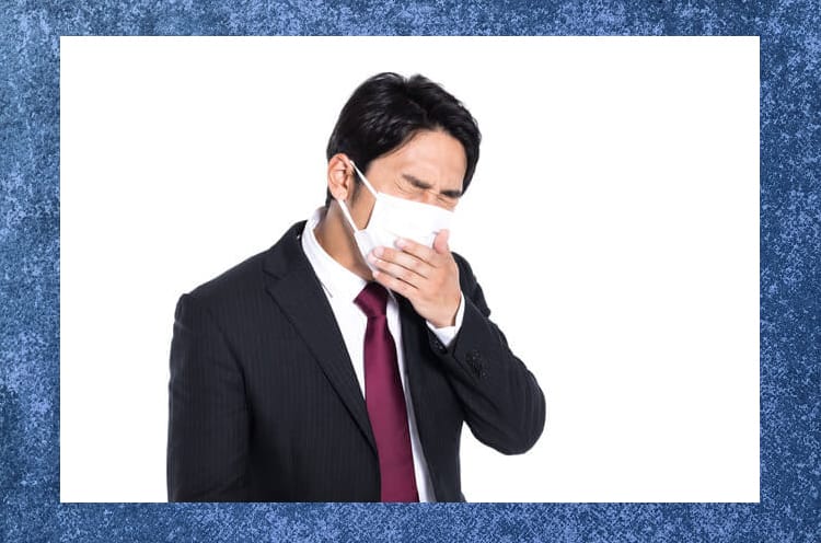 マスクをつけて口を押えて苦しそうにしているスーツ姿の男性