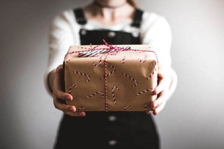 Женщина вручает подарочную коробку