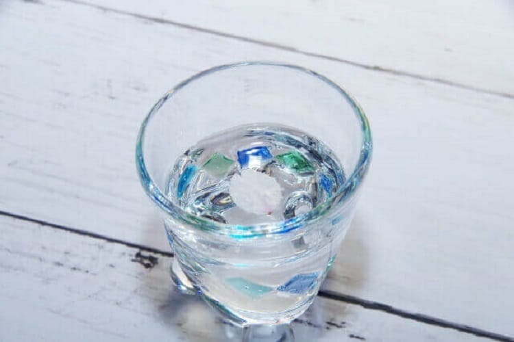 日本酒が入ったグラスの中に桜の花びらが一枚浮いている