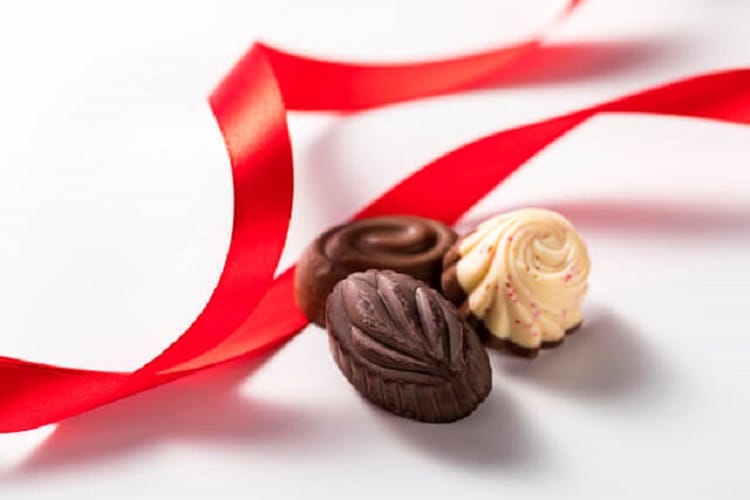 3つの小さなチョコレートと赤いリボン