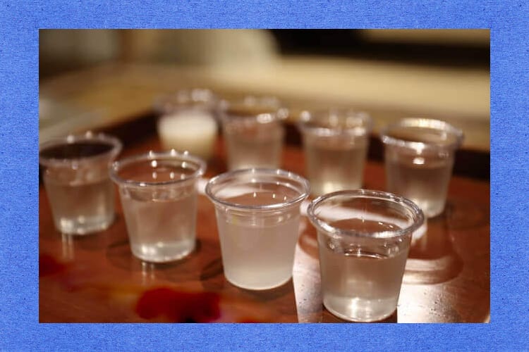 日本酒が入ったたくさんの小さな透明カップ