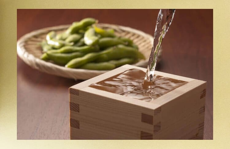 Sake wird in ein Becken gegossen, und daneben steht Edamame