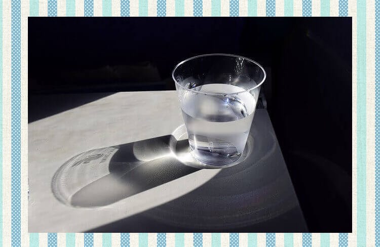 日本酒もしくは水、透明の液体が入ったグラスが光に照らされている