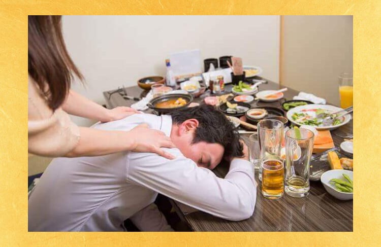 飲み屋のテーブルで酔って寝てしまう男性