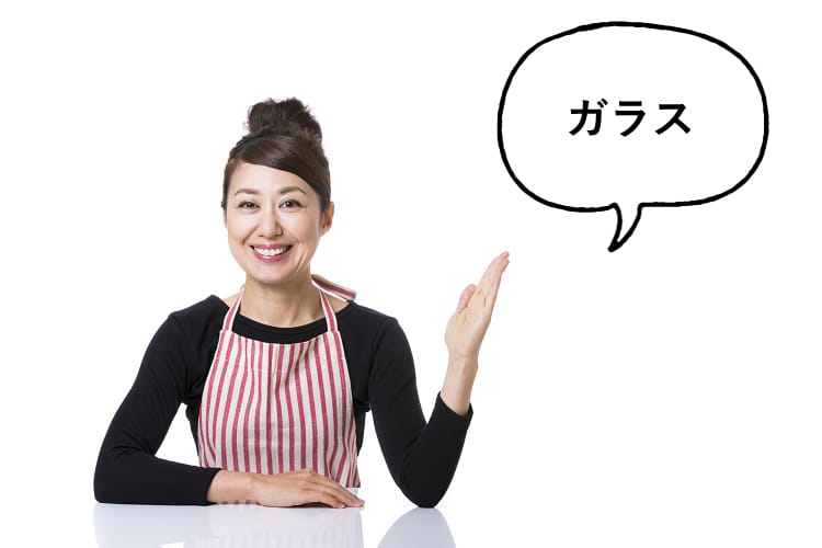 ガラスと話すエプロンをつけた女性