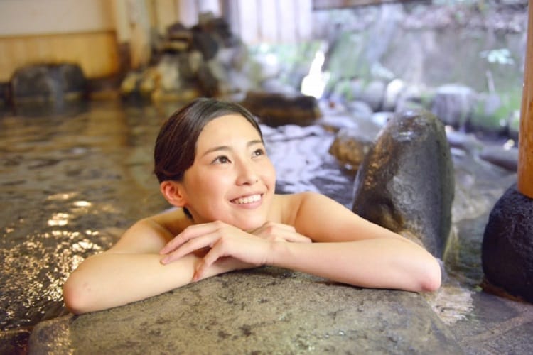 Femme détente dans le bain en plein air avec un sourire